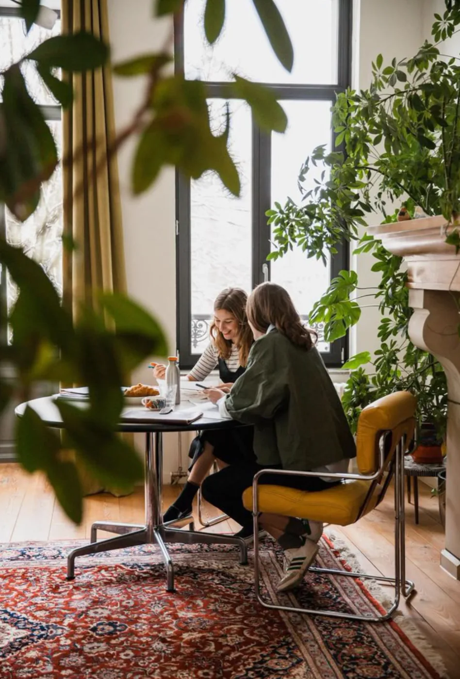 Two people in conversation at a plant-filled table